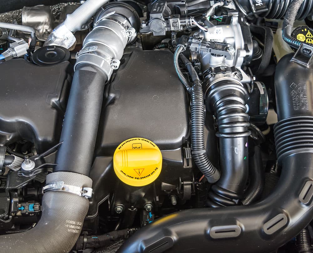 Coolant hoses, clips and the expansion tank cap in an engine bay.