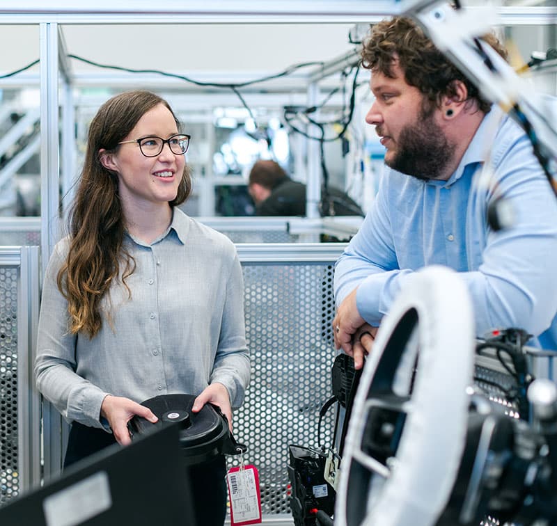 Two engineers discussing a component beside a test rig.