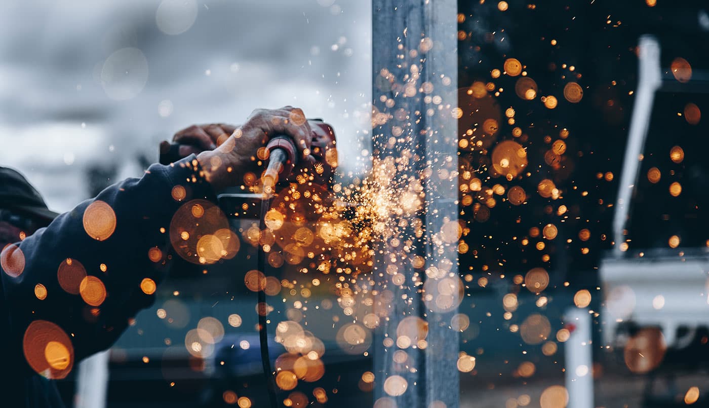 Sparks arc away from an angle grinder as a steel section is cut to size.
