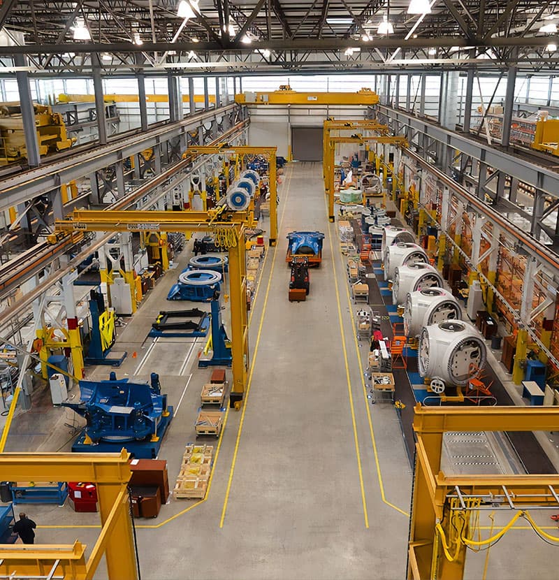 A machining hall, gantry cranes running over rows of part-built industrial assemblies.