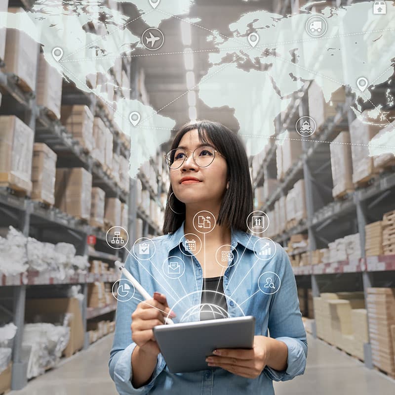 A supply chain manager checking stock on a tablet in a warehouse aisle.