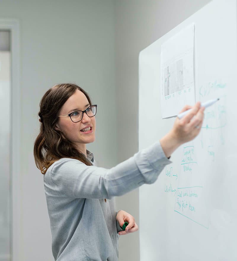 An engineer sketching a process diagram on a whiteboard.